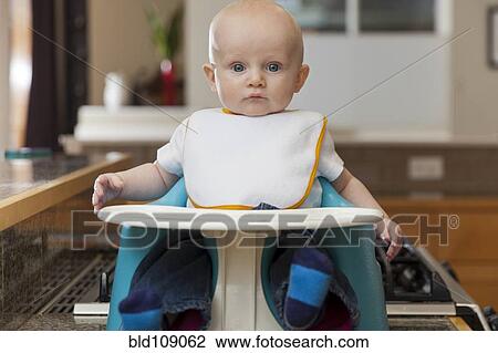 Stock Image - Caucasian baby sitting in high chair. Fotosearch