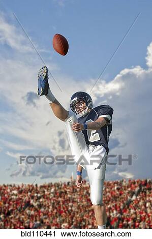 Stock Image - Caucasian football player kicking ball. Fotosearch