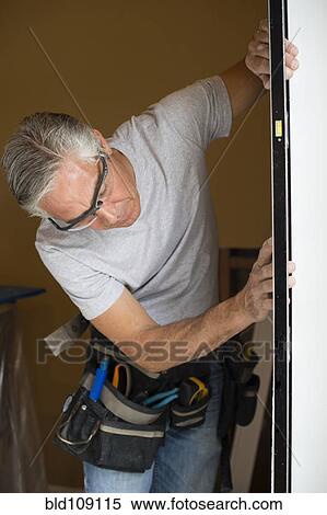 Stock Photography - Caucasian man working on doorway. Fotosearch