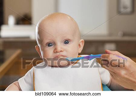 Caucasian mother feeding baby in high chair View Large Photo Image Picture - Caucasian mother feeding baby in high chair. Fotosearch