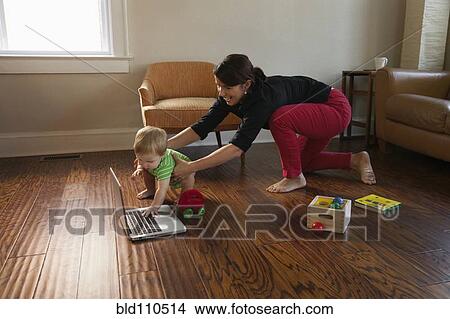 Picture - Caucasian mother keeping toddler son from laptop. Fotosearch