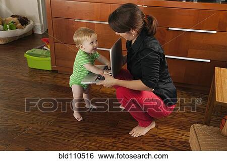 Stock Photograph - Caucasian mother showing toddler laptop. Fotosearch