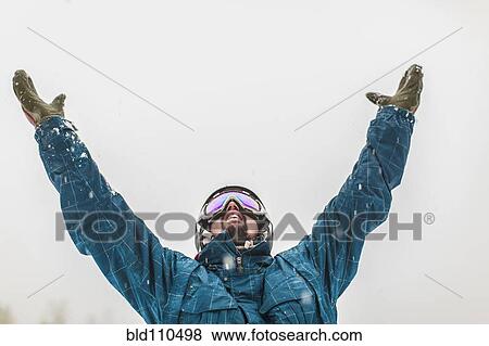 Stock Photo - Caucasian snowboarder cheering in snow. Fotosearch