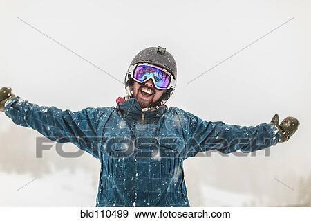 Stock Photo - Caucasian snowboarder cheering in snow. Fotosearch