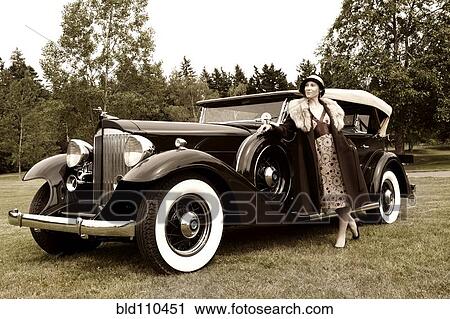Stock Image - Caucasian woman by vintage car. Fotosearch