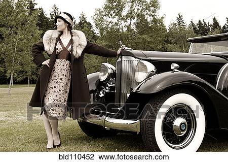 Stock Image - Caucasian woman by vintage car. Fotosearch