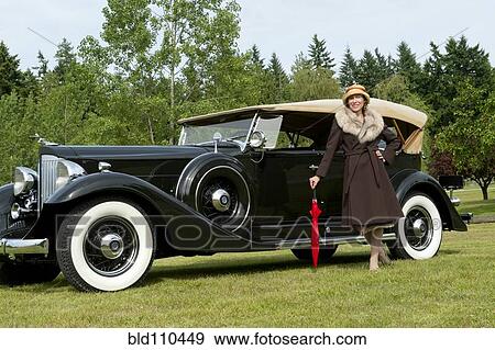 Stock Photo - Caucasian woman by vintage car. Fotosearch