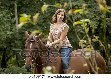 Stock Image - Caucasian woman riding horse outdoors. Fotosearch