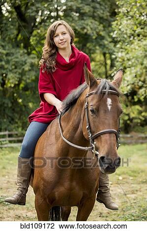 Stock Image - Caucasian woman riding horse outdoors. Fotosearch
