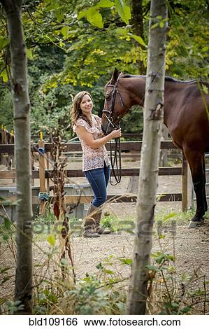 Stock Photograph - Caucasian woman walking horse in pen. Fotosearch