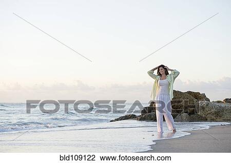 Stock Image - Caucasian woman walking on beach. Fotosearch