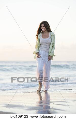 Stock Image - Caucasian woman walking on beach. Fotosearch