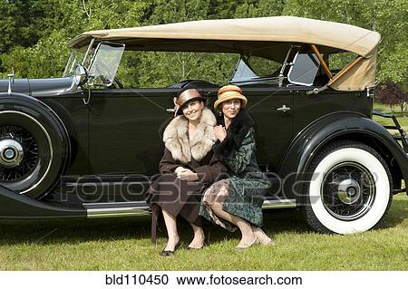 Stock Image - Caucasian women by vintage car. Fotosearch