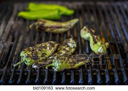 Stock Image - Close up of charred chilies on grill. Fotosearch
