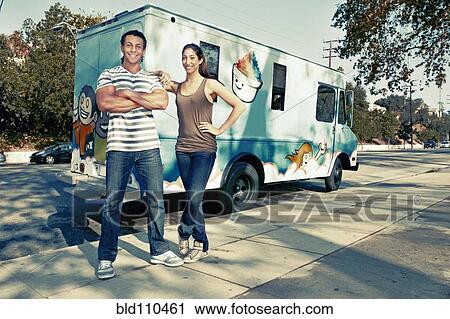 Stock Image - Couple standing by ice cream truck. Fotosearch