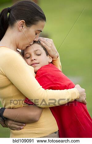 Stock Image - Hispanic mother hugging son. Fotosearch