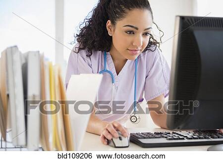 Stock Photograph - Hispanic nurse using computer in hospital. Fotosearch