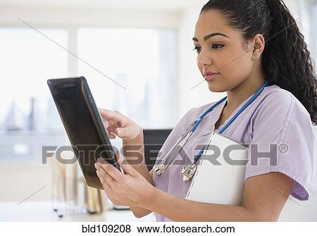 Stock Photo - Hispanic nurse using tablet computer in hospital. Fotosearch