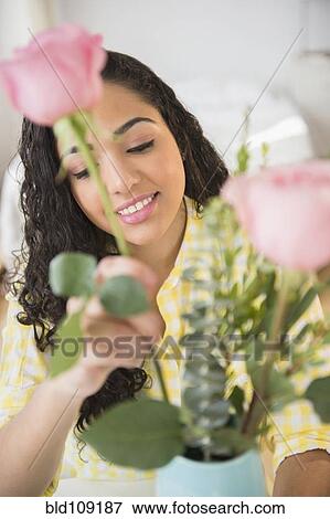 Stock Photo - Hispanic woman arranging flowers in vase. Fotosearch