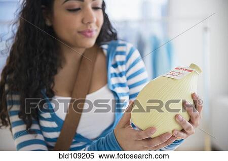 Stock Photography - Hispanic woman examining vase for sale. Fotosearch