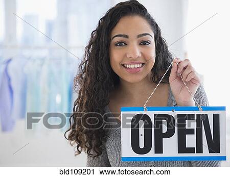 Stock Image - Hispanic woman holding open sign. Fotosearch