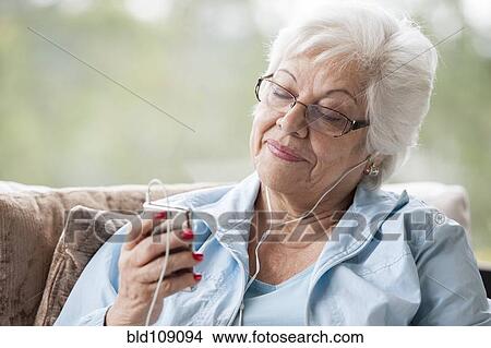 Picture - Hispanic woman listening to mp3 player. Fotosearch