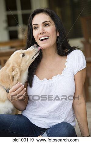 Stock Photo - Hispanic woman playing with dog. Fotosearch