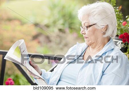 Stock Photography - Hispanic woman reading newspaper. Fotosearch