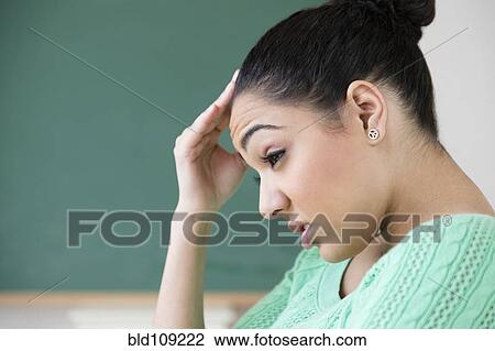 Stock Image - Hispanic woman rubbing forehead. Fotosearch