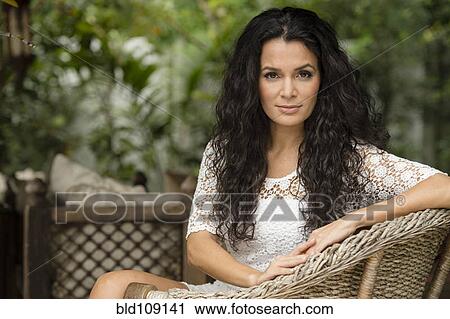 Stock Image - Hispanic woman sitting in armchair. Fotosearch