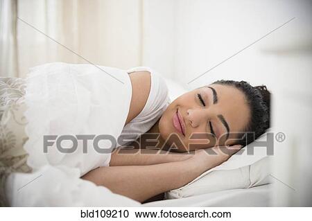 Stock Image - Hispanic woman sleeping in bed. Fotosearch