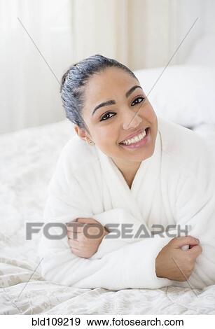 Stock Photo - Hispanic woman smiling on bed. Fotosearch