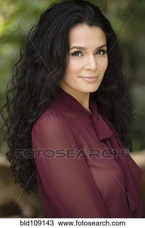 Stock Image - Hispanic woman smiling outdoors. Fotosearch