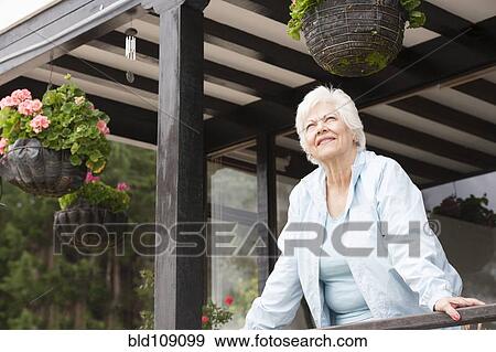 Stock Photo - Hispanic woman standing on porch. Fotosearch