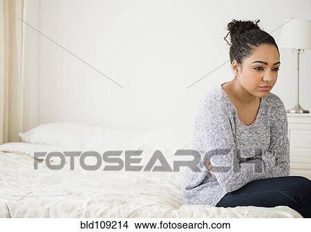 Picture - Hispanic woman thinking on bed. Fotosearch
