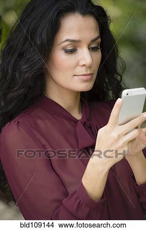 Picture - Hispanic woman using cell phone. Fotosearch