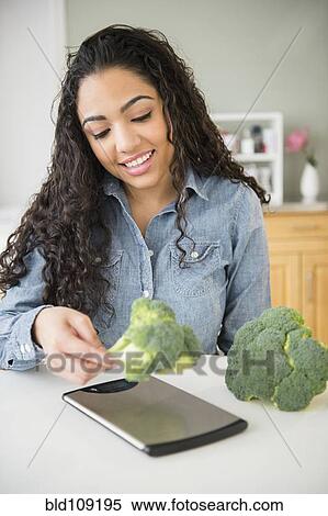 Hispanic woman weighing broccoli in kitchen View Large Photo Image Stock Photography - Hispanic woman weighing broccoli in kitchen. Fotosearch