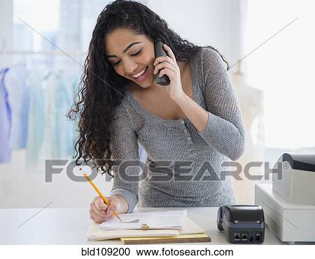 Stock Image - Hispanic woman working in laundromat. Fotosearch