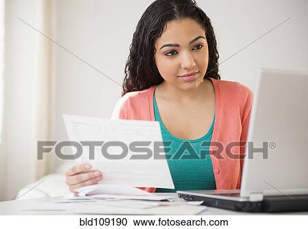 Stock Image - Hispanic woman working on laptop. Fotosearch