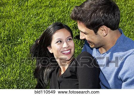 Mixed race couple relaxing together in grass View Large Photo Image Stock Photo - Mixed race couple relaxing together in grass. Fotosearch