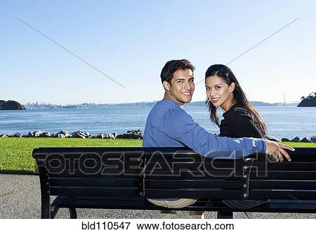 Mixed race couple sitting on park bench View Large Photo Image Stock Photo - Mixed race couple sitting on park bench. Fotosearch