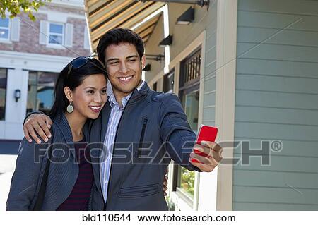 Mixed race couple using cell phone outdoors View Large Photo Image Picture - Mixed race couple using cell phone outdoors. Fotosearch