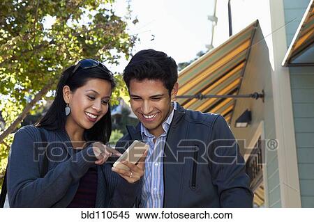 Mixed race couple using cell phone outdoors View Large Photo Image Stock Photography - Mixed race couple using cell phone outdoors. Fotosearch
