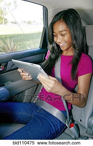 Stock Photography - Mixed race girl using digital tablet in car. Fotosearch