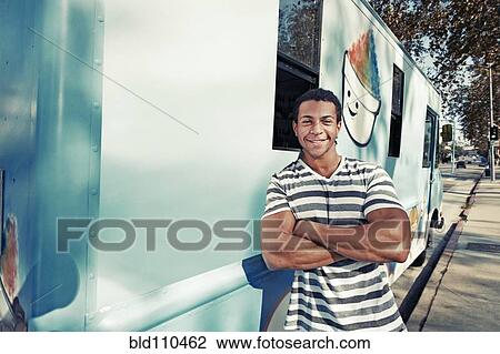 Stock Image - Mixed race man leaning on ice cream truck. Fotosearch