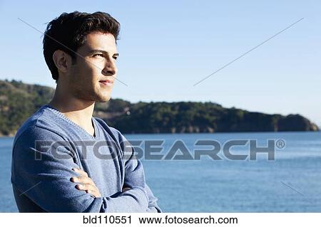 Stock Image - Mixed race man overlooking waterfront. Fotosearch