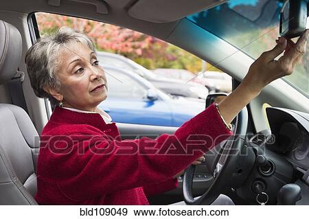 Stock Photo - Mixed race woman adjusting car mirror. Fotosearch