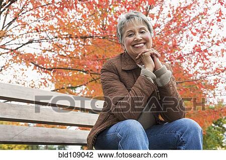 Stock Image - Mixed race woman on park bench. Fotosearch