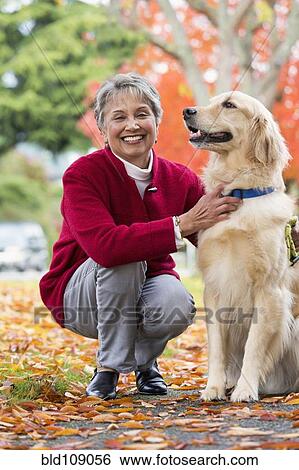 Stock Photograph - Mixed race woman petting dog. Fotosearch