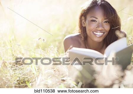 Mixed race woman reading in grass View Large Photo Image Stock Photo - Mixed race woman reading in grass. Fotosearch